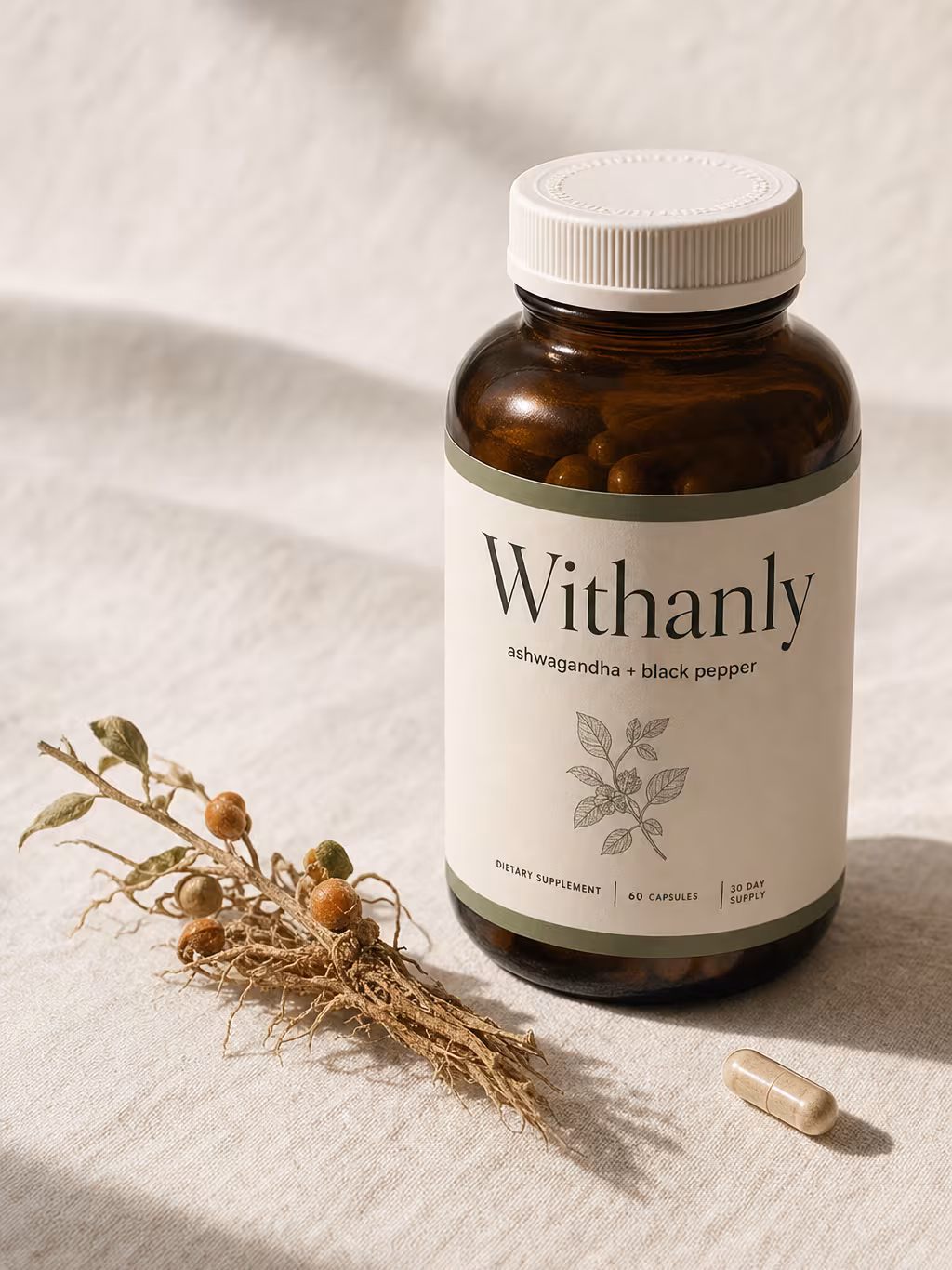 Withanly ashwagandha + black pepper bottle on cream linen with a sprig of dried root and a single capsule, soft window light